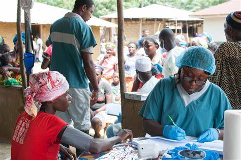 African healthcare workers in blue scrubs providing medical services to community members in rural Liberia